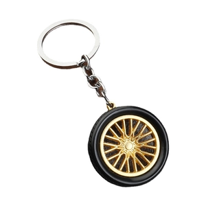 Creative PVC tire keychain with golden wheel rim and black rubber texture on white background