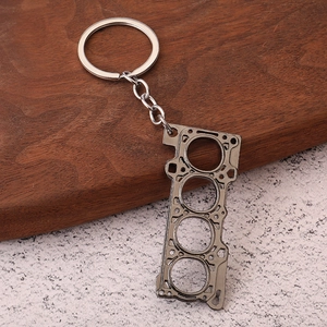 Detailed view of gunmetal engine cylinder head gasket keychain on a wooden surface