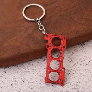 Macro shot of red anodized metal engine cylinder gasket keychain with metallic texture