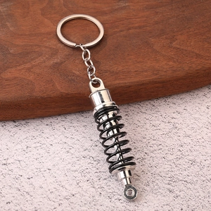 Detailed view of shock absorber keychain with black spring and silver metallic finish