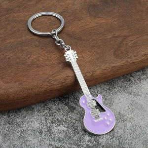 Detail shot of a purple electric guitar keychain with polished metal neck and round ring