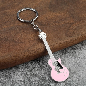 Detail of a pink electric guitar keychain with silver chain on rustic wood background