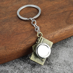 Vintage camera alloy keychain with bronze finish and silver lens on rustic wood
