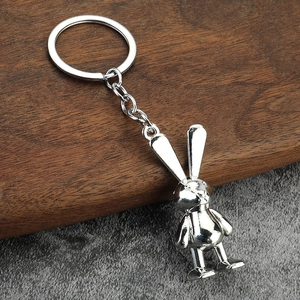Polished silver space bunny keychain on minimalist dark wood and gray background