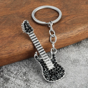 Sparkling silver guitar keychain with black rhinestones on a rustic wooden background