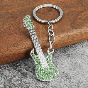 Close-up of a silver guitar keychain with sparkling green rhinestones and metal ring