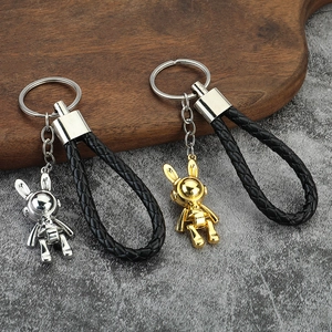 Creative space bunny metal keychains in gold and silver with woven leather strap on a tray