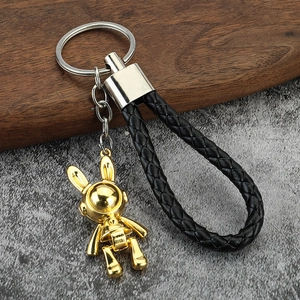 Detail of creative golden astronaut bunny keychain with black braided leather strap
