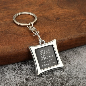 Detail view of the silver metal square photo frame keychain with lobster clasp on wood background