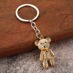 Luxury gold bear keychain with sparkling rhinestones on a rustic industrial background