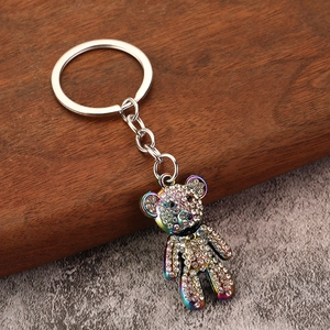 Sparkling rhinestone bear keychain with rainbow metallic finish on a rustic wooden floor