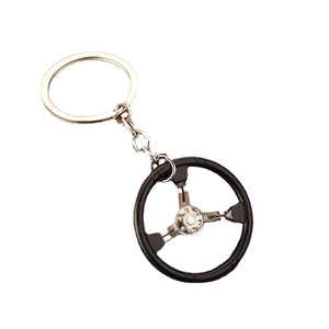 Racing steering wheel keychain with three-spoke silver frame and black rim on white background