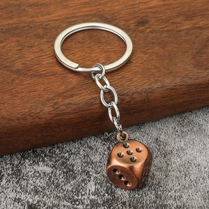 Close-up of vintage bronze dice keychain with metallic finish on a textured background