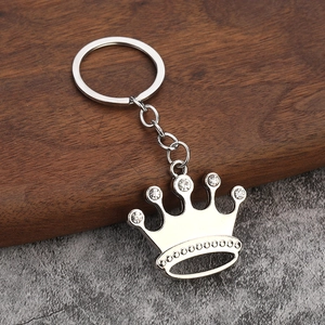 Sparkling silver crown keychain with embedded rhinestones on a rustic wooden surface
