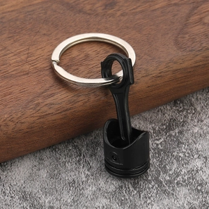 Macro detail of a creative black matte car engine piston and connecting rod keychain