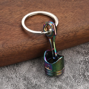 Engine piston keychain with rainbow gradient plating on a metallic industrial design