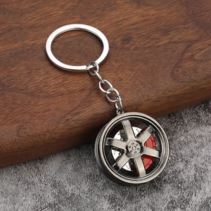 Close-up of alloy car wheel hub keychain with red brake caliper on textured background
