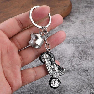 Creative metal motorcycle keychain with helmet pendant in silver finish held by hand
