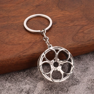 Polished silver alloy car rim keychain with five-spoke wheel pendant on wooden background