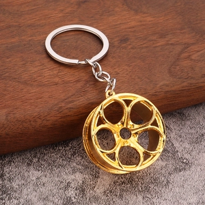 Detail of a golden five-spoke car wheel rim keychain with a polished silver ring