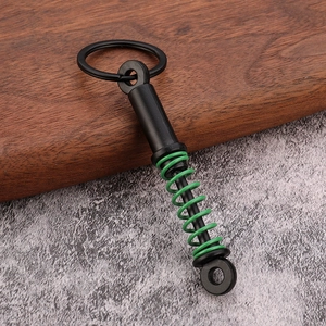 Detailed view of car shock absorber keychain with green spring on stone and wood