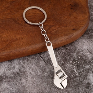 Miniature adjustable wrench keychain in polished silver metal on a rustic wood background
