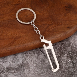 Detailed view of mini handsaw keychain tool with silver finish on rustic wood texture