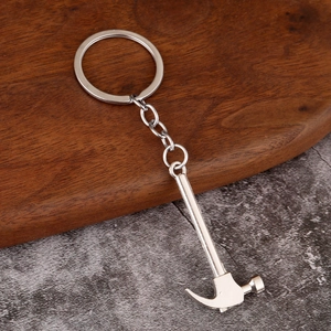 Polished silver metal keychain with miniature claw hammer tool on marble background