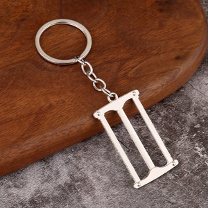 Detailed view of mini silver alloy hand saw keychain pendant on rustic wooden background