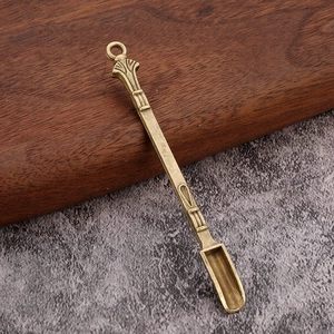 Macro detail of a vintage brass miniature spoon with intricate textured handle and ring top