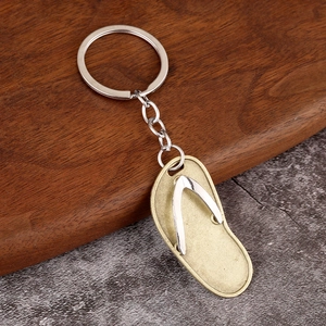 Detail of creative flip flop keychain with gold sole and silver strap on wooden base