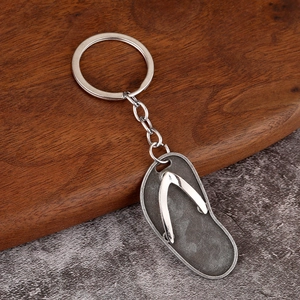 Macro shot of a flip-flop shaped metal keychain with vintage silver finish on wood surface