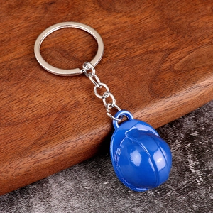 Close-up of a blue mini safety helmet keychain with a silver metal ring on wood background