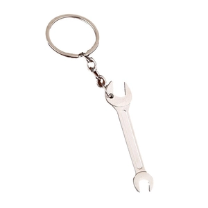 Miniature silver metal wrench keychain tool pendant with polished finish on white background