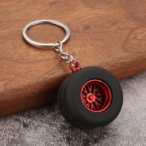 Detailed macro view of the 3D car tire keychain with red rim on a textured surface