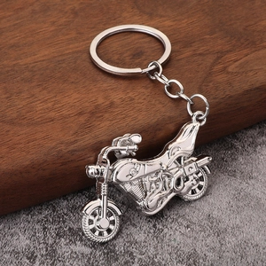 Polished silver alloy motorcycle keychain detailing on rustic wood and stone background