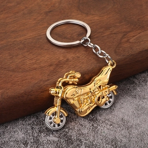 Close-up of retro alloy motorcycle keychain with gold plating and silver wheels