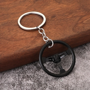 Racing steering wheel keychain model with silver metal chain on textured background