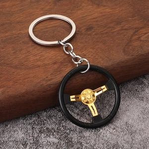Macro detail of a 3-spoke racing steering wheel keychain in black and gold metal