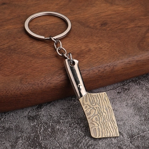 Detailed close-up of kitchen knife keychain with Damascus steel patterns on dark gold blade