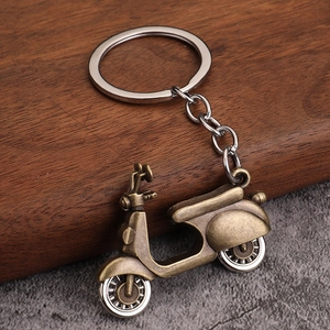 Macro detail of a vintage bronze scooter keychain on a rustic wood and stone background