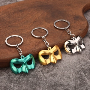 Three phantom opera mask metal keychains in green, gold and silver on a wooden board