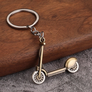 Detail of vintage bronze scooter keychain with retro metal texture on wooden surface