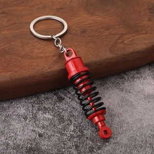 Portachiavi creativo in metallo a forma di ammortizzatore con molla rossa su pietra