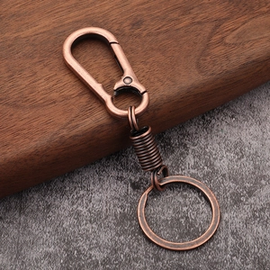Detail of vintage copper spring keychain with lobster clasp on a textured background