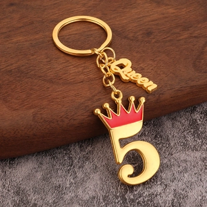 Detail van een gouden Queen sleutelhanger met rode kroon en cijfer 5 bedeltje