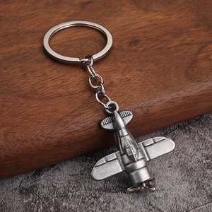 Close-up of vintage silver fighter plane keychain with detailed wings and propeller