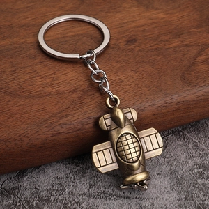 Macro detail of vintage bronze airplane keychain on a textured wooden background