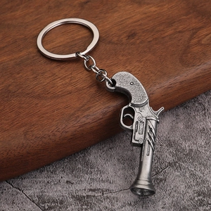 Detailed view of a vintage metal pistol keychain on a rustic wooden and stone background