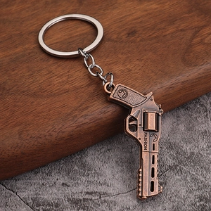 Vintage bronze revolver pistol keychain made of metal alloy on a rustic wooden background